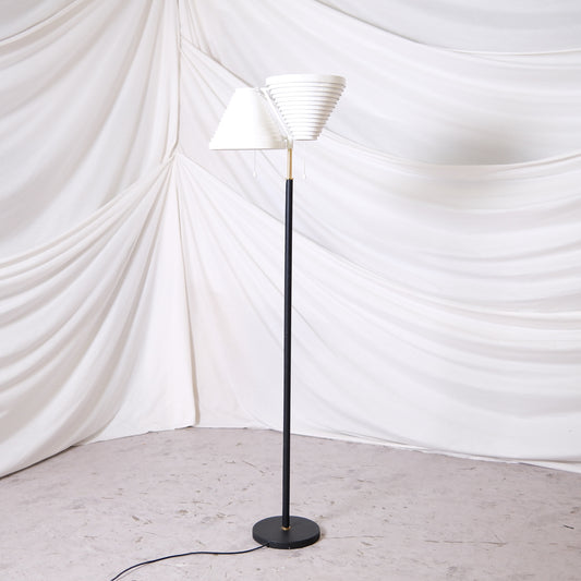 Vintage Artek A810 floor lamp by Alvar Aalto with white layered shades, black stem and brass details. Finnish design lighting from Helsinki, worldwide shipping available.