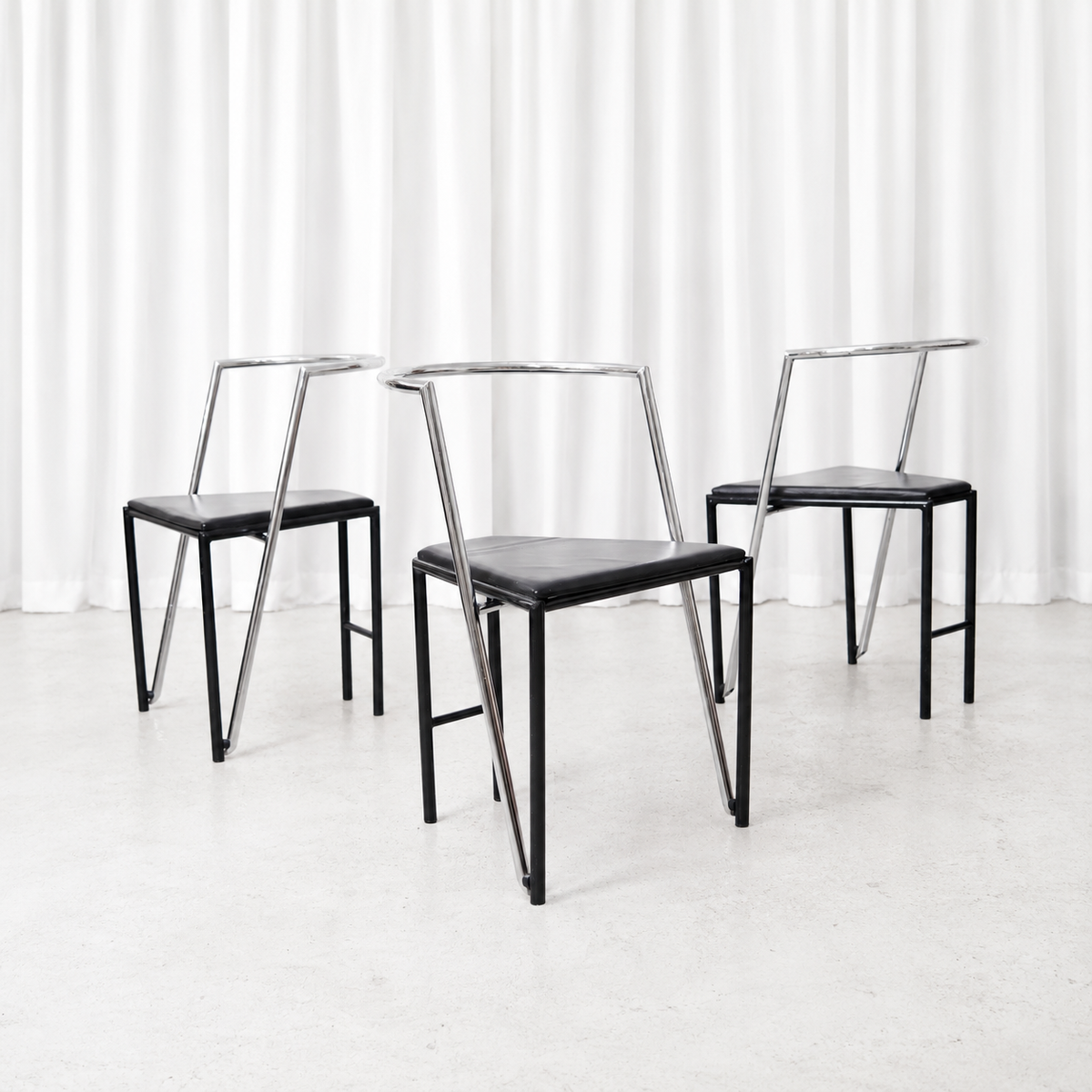 Vintage dining chairs with polished chrome frames, black metal details and black leather seats.