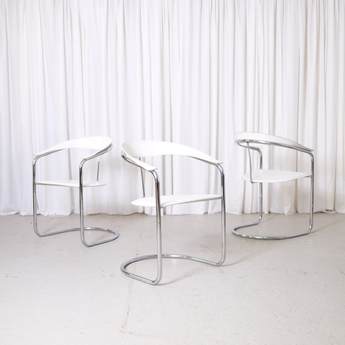 Vintage Italian chrome and white leather dining chairs with curved armrests and open metal frames
