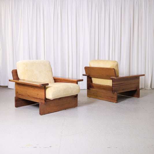Pair of vintage Scandinavian pine armchairs with butter velvet upholstery, low wooden frames, and wide armrests.