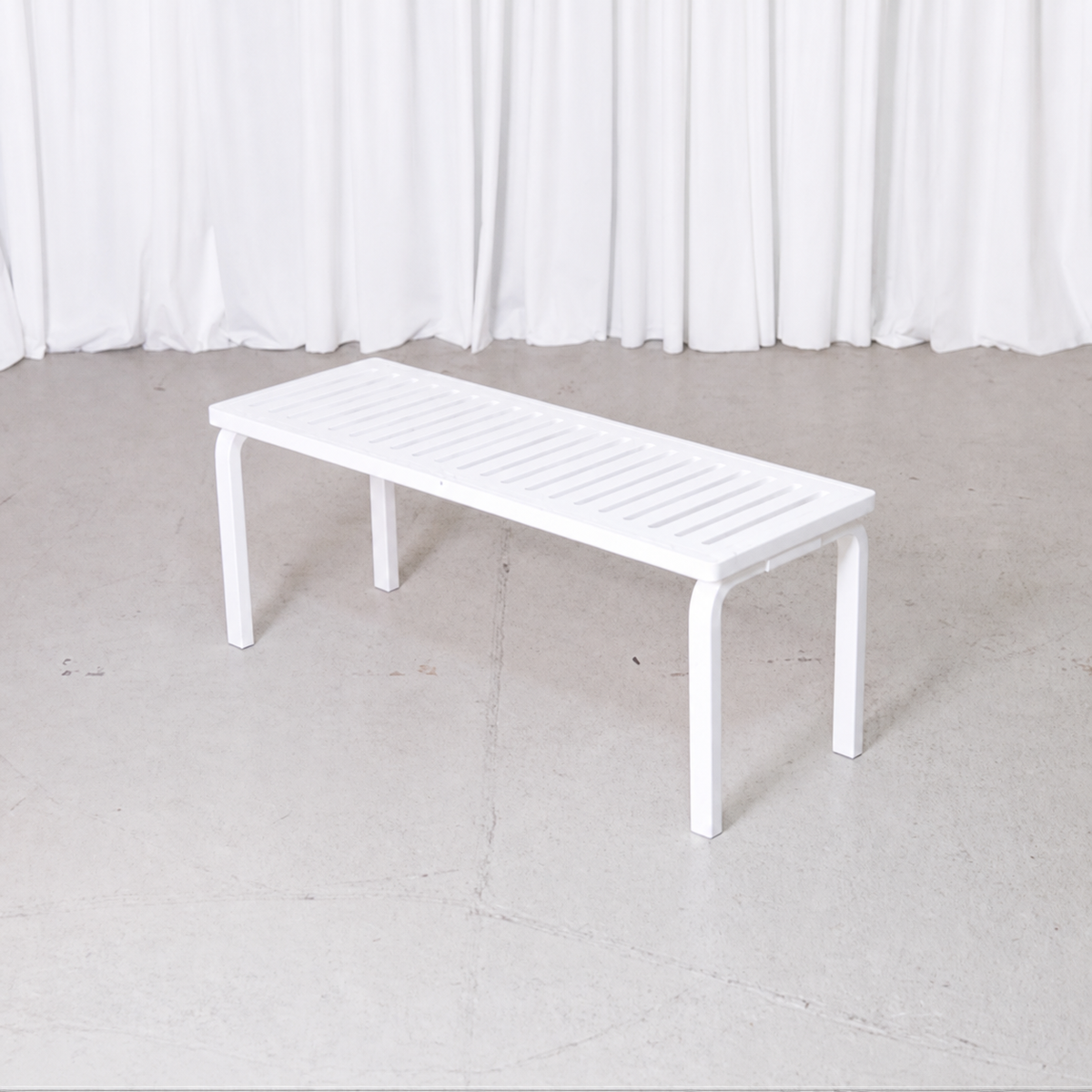White Artek 153A slatted bench by Alvar Aalto, angled view