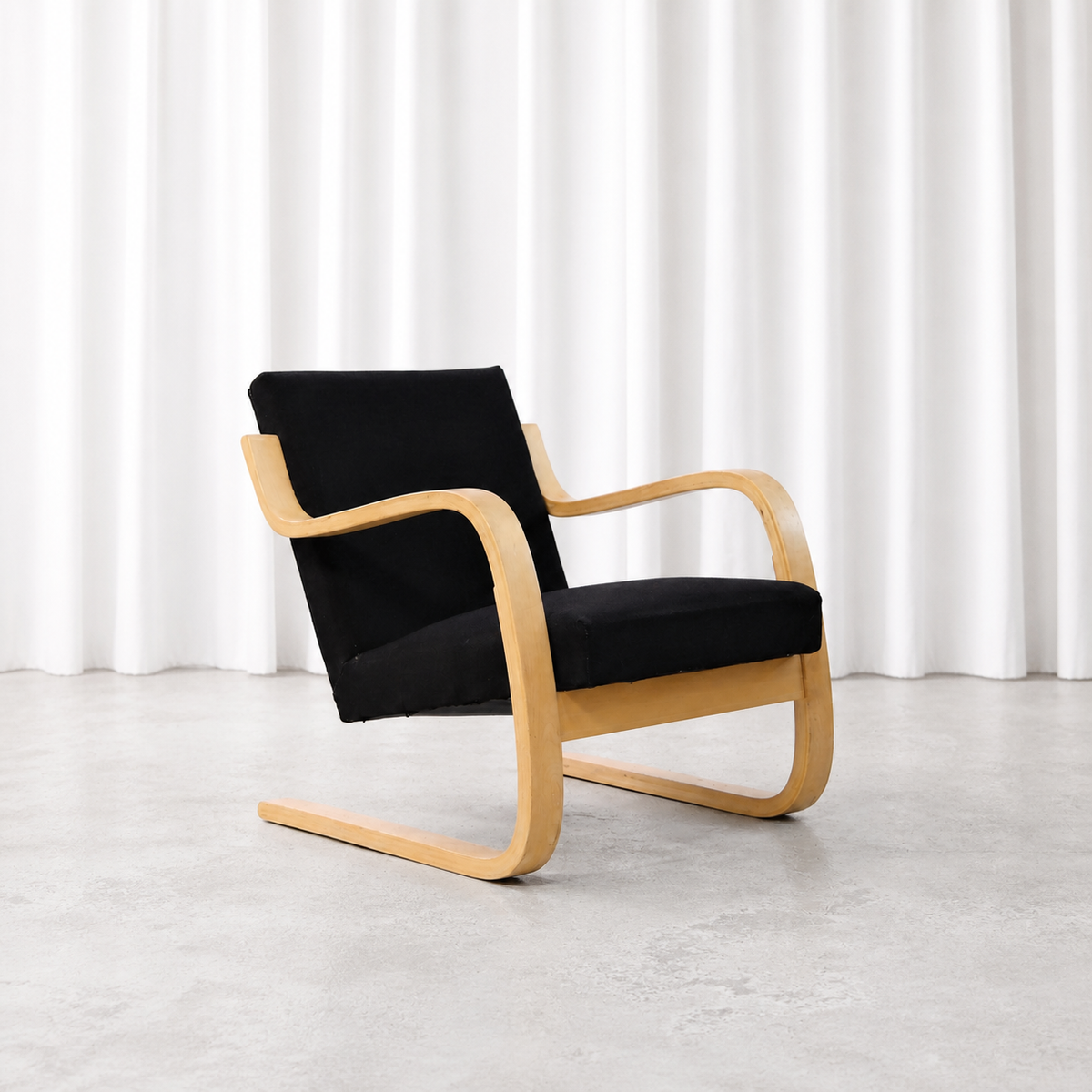 Front three-quarter view of a 1960s Artek 402 armchair in black fabric