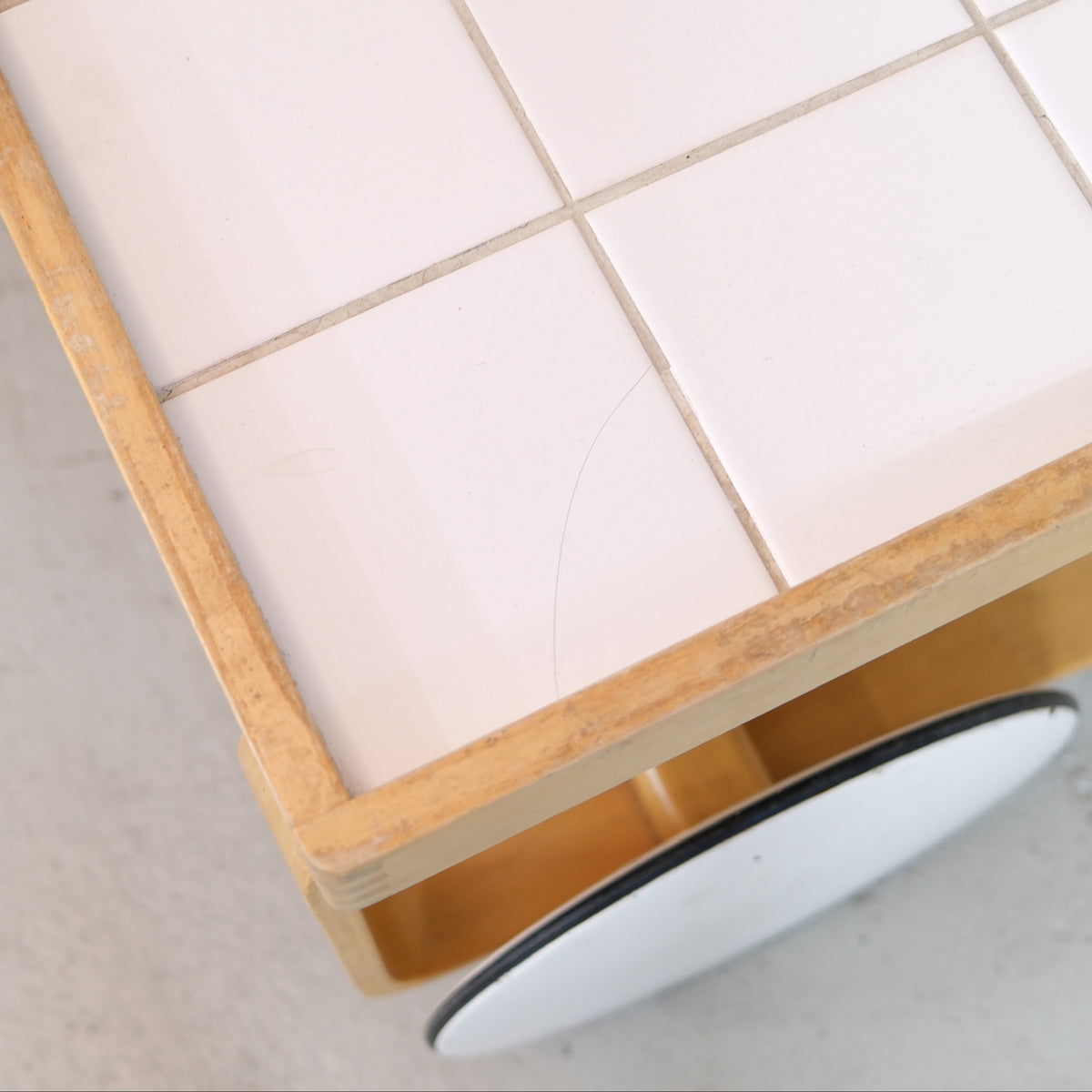 Hairline scratch and wear on the white ceramic tiled top