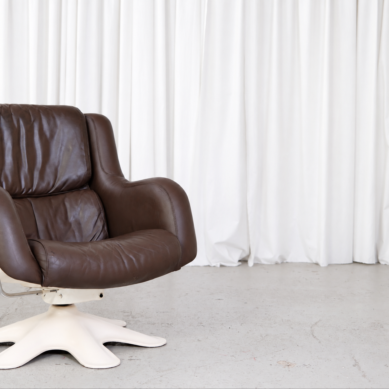 Brown leather upholstery and white fibreglass base detail on Yrjö Kukkapuro 418 chair